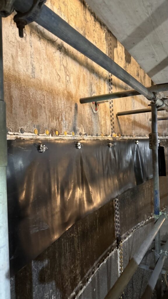 Adjacent panels not being coated were temporarily protected with rubber sheeting.